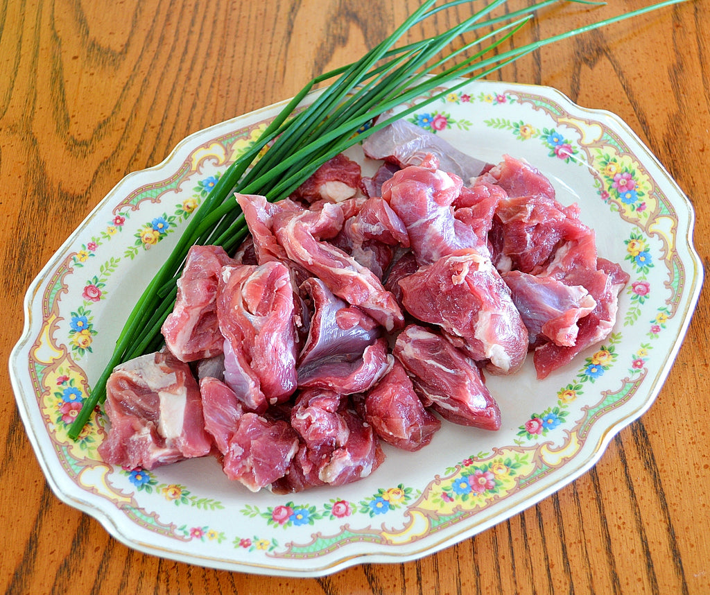 chunks of lamb, perfect for stew, set on floral plate with garnishes